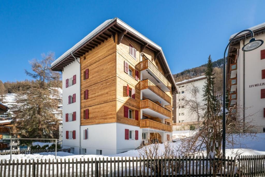 Un edificio a più piani con balconi e terreno innevato.