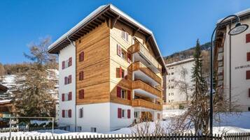 Un edificio a più piani con balconi e terreno innevato.
