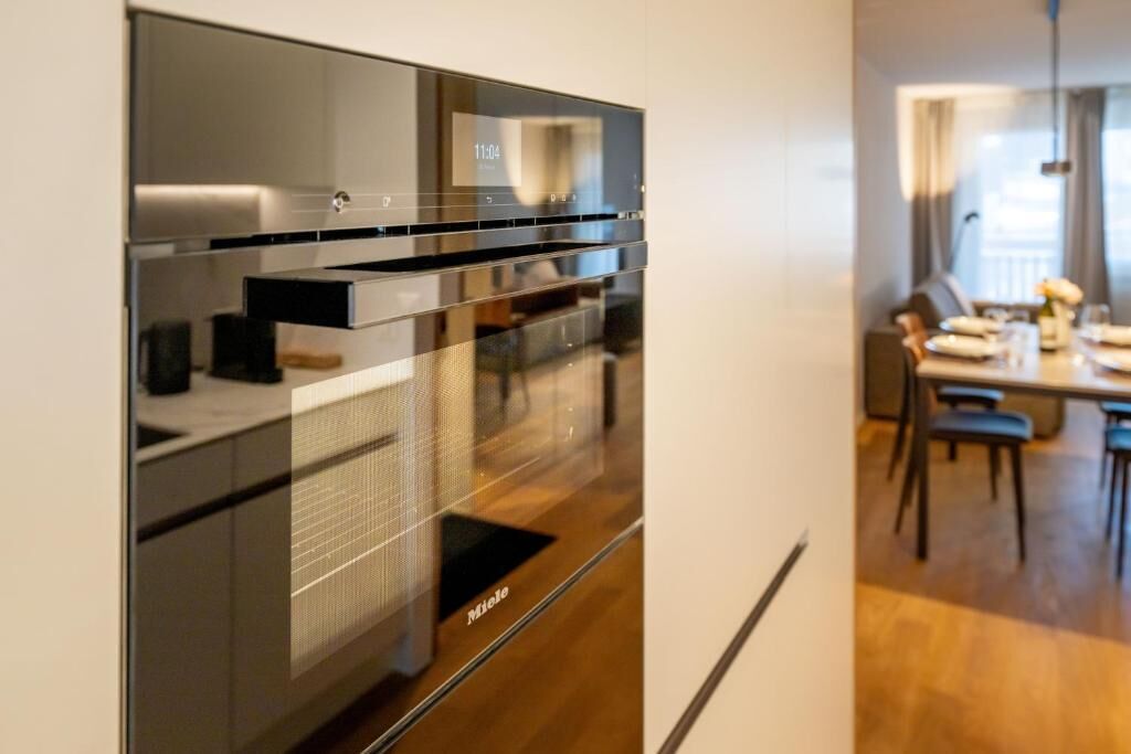 Uma cozinha moderna com forno embutido e uma área de refeições com mesa e cadeiras.