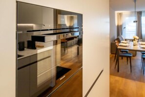 Uma cozinha moderna com forno embutido e uma área de refeições com mesa e cadeiras.
