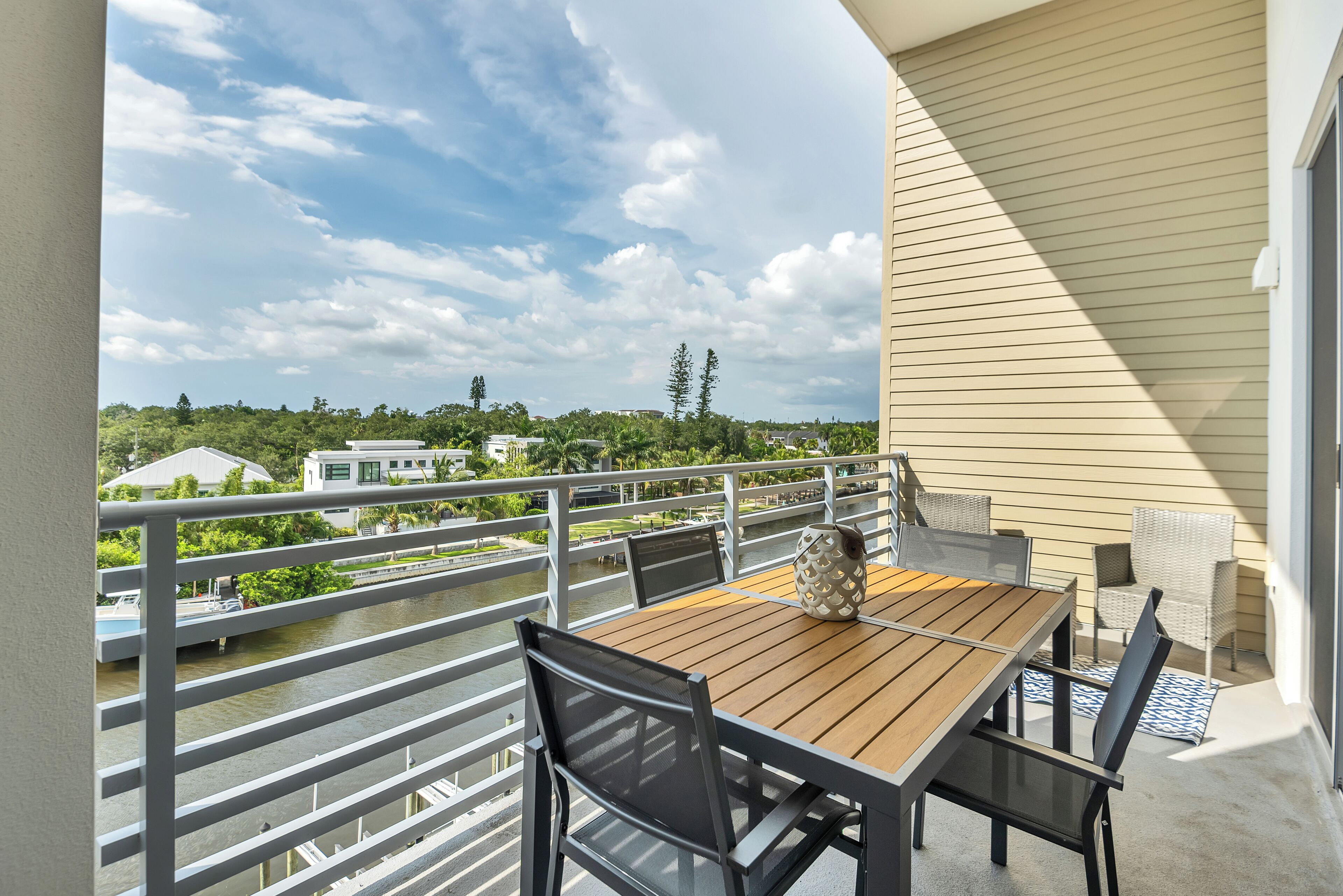 A balcony with a table and chairs, overlooking a river and buildings.