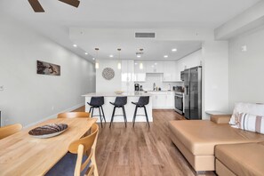 Eine moderne Küche mit weißen Schränken, einem Edelstahl-Kühlschrank und einer zentralen Kochinsel mit Barhocker.