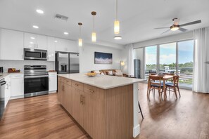A modern kitchen with stainless steel appliances, a wooden island, and a dining area with a view. - Sarasota Top Floor Bay & Canal Views + Kayaks (Sarasota)