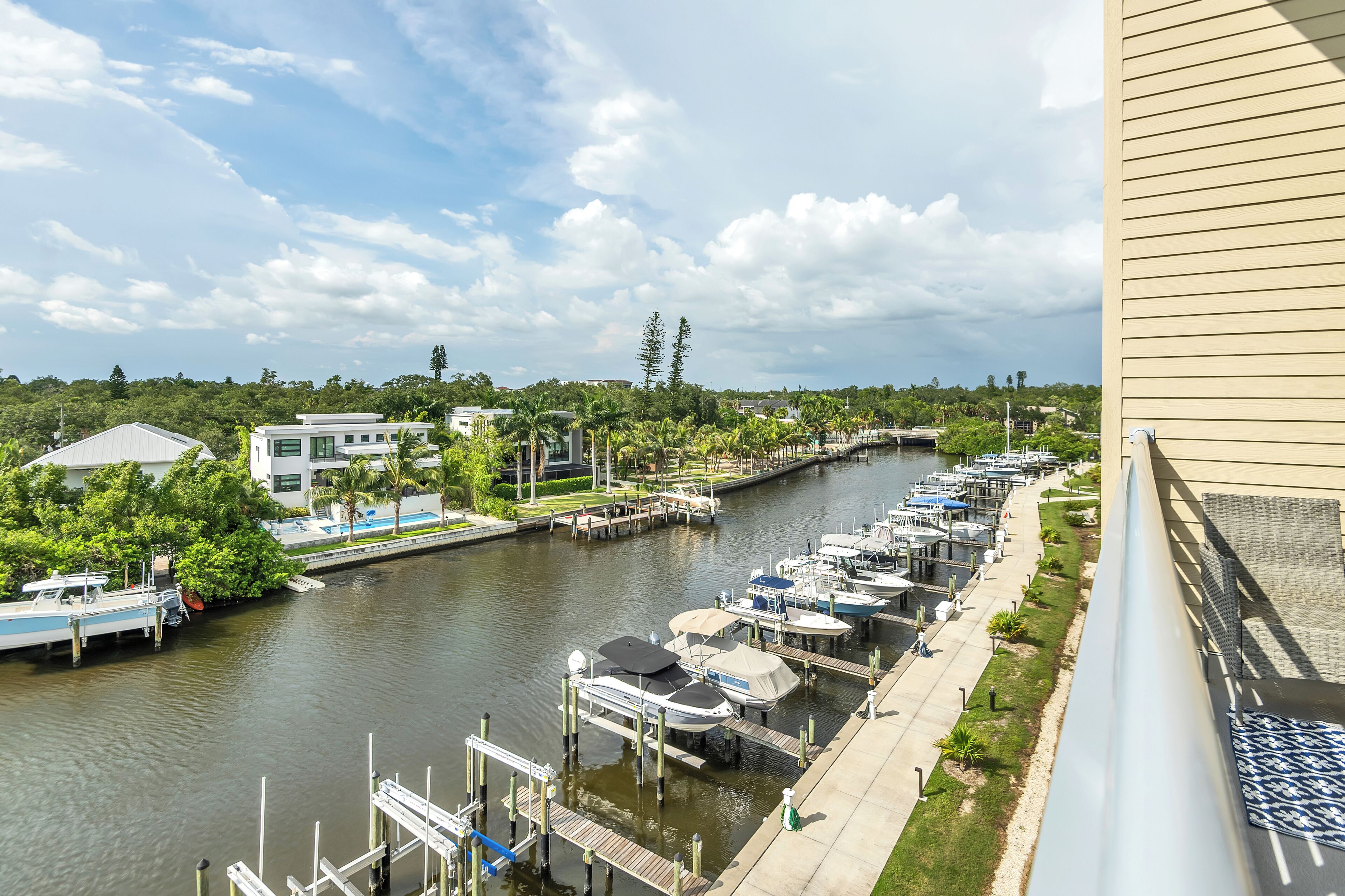 A marina with boats docked, a swimming pool, and a view of the surrounding greenery and buildings.