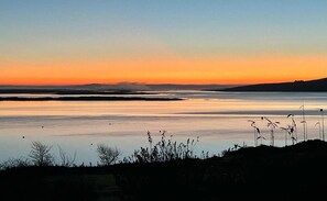 Ruhige Wasseroberfläche spiegelt den Himmel während des Sonnenuntergangs.