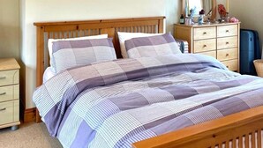 A bedroom with a wooden bed, a dresser, a mirror, and a framed picture on the wall. - Oyster Cove Kilkerrin stunning views (Kilkerrin)