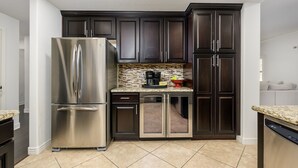 A modern kitchen with dark cabinetry, stainless steel appliances, and a tiled backsplash. - Highly desired Desert Ridge condo on 1st level- no stairs, large patio (Phoenix)