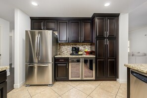 Uma cozinha moderna com armários escuros, eletrodomésticos de aço inoxidável e painel de azulejos.