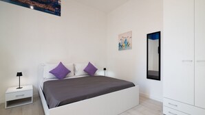 A bedroom with a bed, nightstand, wardrobe, and a painting on the wall. - Lovely 22 sqm studio apartment, for two guests, located on the second floor of a renovated historic building (no elevator). The property enjoys a strategic location just steps away from the Policlinico hospital, the Ballarò district, and the city center (Palermo)