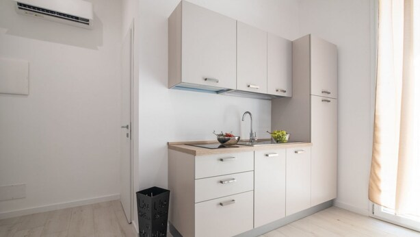 A modern kitchen with a built-in stove, a sink, and a window with curtains. - Lovely 22 sqm studio apartment, for two guests, located on the second floor of a renovated historic building (no elevator). The property enjoys a strategic location just steps away from the Policlinico hospital, the Ballarò district, and the city center (Palermo)