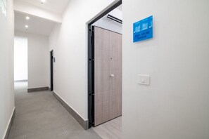 Ein Flur mit einer geschlossenen Tür, einem Lichtschalter und einem Schild mit der Aufschrift Azure Room.