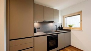 Una cocina compacta con horno integrado, un lavabo y una ventana con una planta.