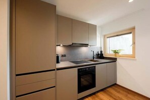 A compact kitchen with a built-in oven, a sink, and a window with a plant. - Apartment Valschaviel 12 (Gaschurn)