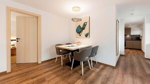 Un comedor moderno con piso de madera, una mesa con cuatro sillas y una obra de arte contemporánea en la pared.