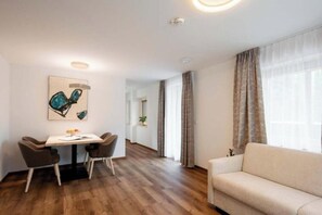 A modern living room with a sofa, a dining table with chairs, and a painting on the wall. - Apartment Valschaviel 12 (Gaschurn)