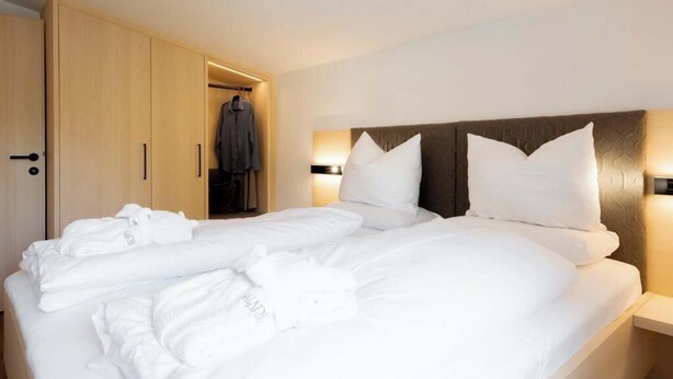 Ett hotellrum med en säng, en garderob och en klädstång.
