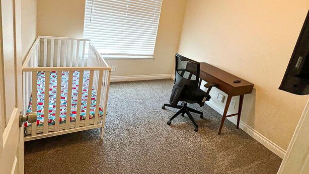 A room with a crib, a desk, and a window with blinds. - Simi Valley Pool Home Spacious & Fully Furnished 4bd 2ba (Simi Valley)