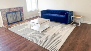 A living room with a blue sofa, a white coffee table, a patterned rug, and a small white side table. - Simi Valley Pool Home Spacious & Fully Furnished 4bd 2ba (Simi Valley)