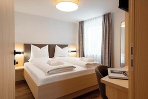 Ein Hotelzimmer mit Bett, Nachttischen, einem Schreibtisch und einem Fernseher.