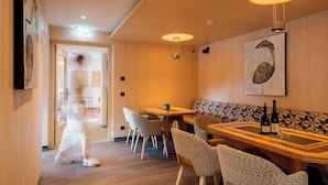 A restaurant interior with wooden flooring, patterned wall seating, and pendant lighting. - Versail D1 Apartment (Gaschurn)