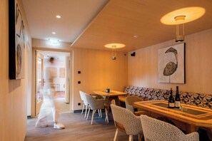 Ein Restaurantinneres mit Holzboden, gemusterten Sitzbänken und Pendelleuchten.