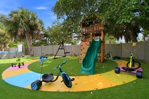 Ein Spielplatz mit Rutsche, Kletterwand und Dreirad.