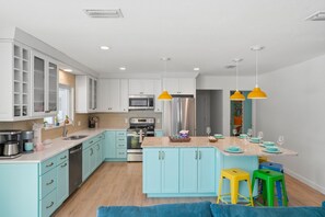 Une cuisine moderne avec des meubles de couleur bleu clair, des appareils en acier inoxydable et un îlot central doté de tabourets.