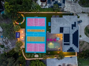 An aerial view of a property with multiple tennis courts, a swimming pool, and a building with solar panels. - Full-Size BBall Court & 2x Pickleball Court Resort, Pool, Hot Tub & Mini Golf! (Bradenton)