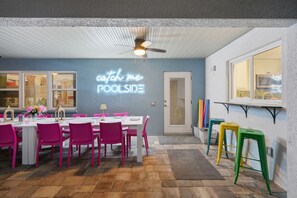 Un espace repas agrémenté d'un néon, d'un ventilateur de plafond et offrant une vue sur la cuisine par le biais d'une fenêtre.