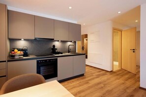 Eine moderne Küche mit integrierten Geräten, ein Essbereich mit Tisch und Stühlen und ein Holzboden.