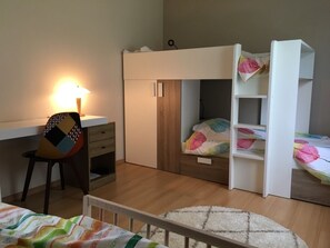 Quarto de criança com beliches, escrivaninha e cadeira.