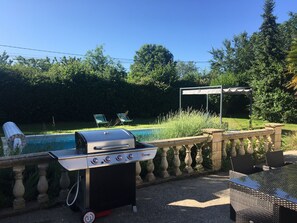 Grilli, jossa on tunnettu tuotemerkki, uima-allas, ulkokalusteita ja pergola.
