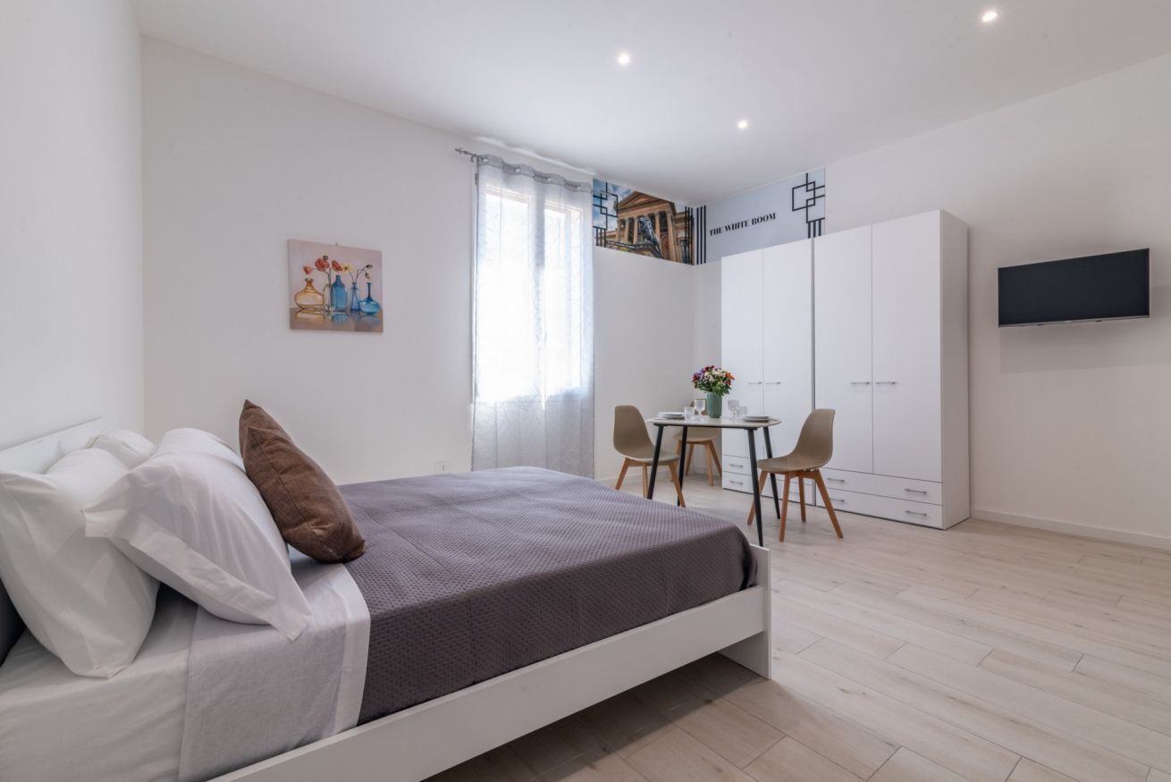 A modern bedroom with a bed, a desk, and a wardrobe.