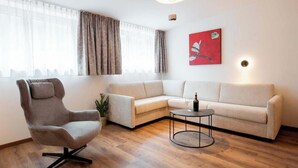 A modern living room with a sectional sofa, a swivel chair, a small round table, and a potted plant. - Apartment Zamangspitze 32 (Gaschurn)