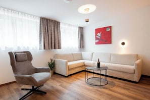 A modern living room with a sectional sofa, a swivel chair, a small round table, and a potted plant. - Apartment Zamangspitze 32 (Gaschurn)