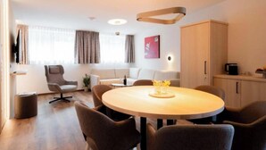 A modern hotel room with a round dining table, a sofa, a TV, and a cabinet. - Apartment Zamangspitze 32 (Gaschurn)