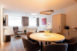 A modern hotel room with a round dining table, a sofa, a TV, and a cabinet. - Apartment Zamangspitze 32 (Gaschurn)