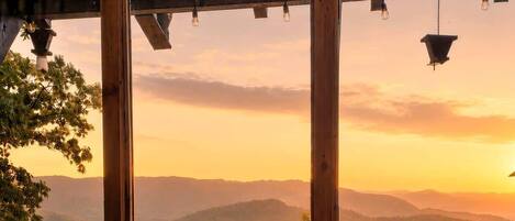 A cozy outdoor seating area with a view of distant hills during sunset.