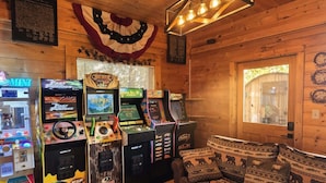 A room with wooden walls, a sofa with animal prints, and arcade games including 'The Fast and the Furious' and 'Big Buck Hunter'. - Smoky Mtn Views  Hot Tub  Sauna Game Room (Sevierville)