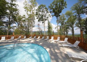 Poolbereich mit Liegestühlen und Blick auf Bäume und Berge.