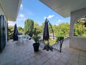 A covered outdoor area with a table and chairs, a potted plant, and a swing chair. - Logement 100m² - La Villa' Tyno - 9 couchages (La Teste-de-Buch)