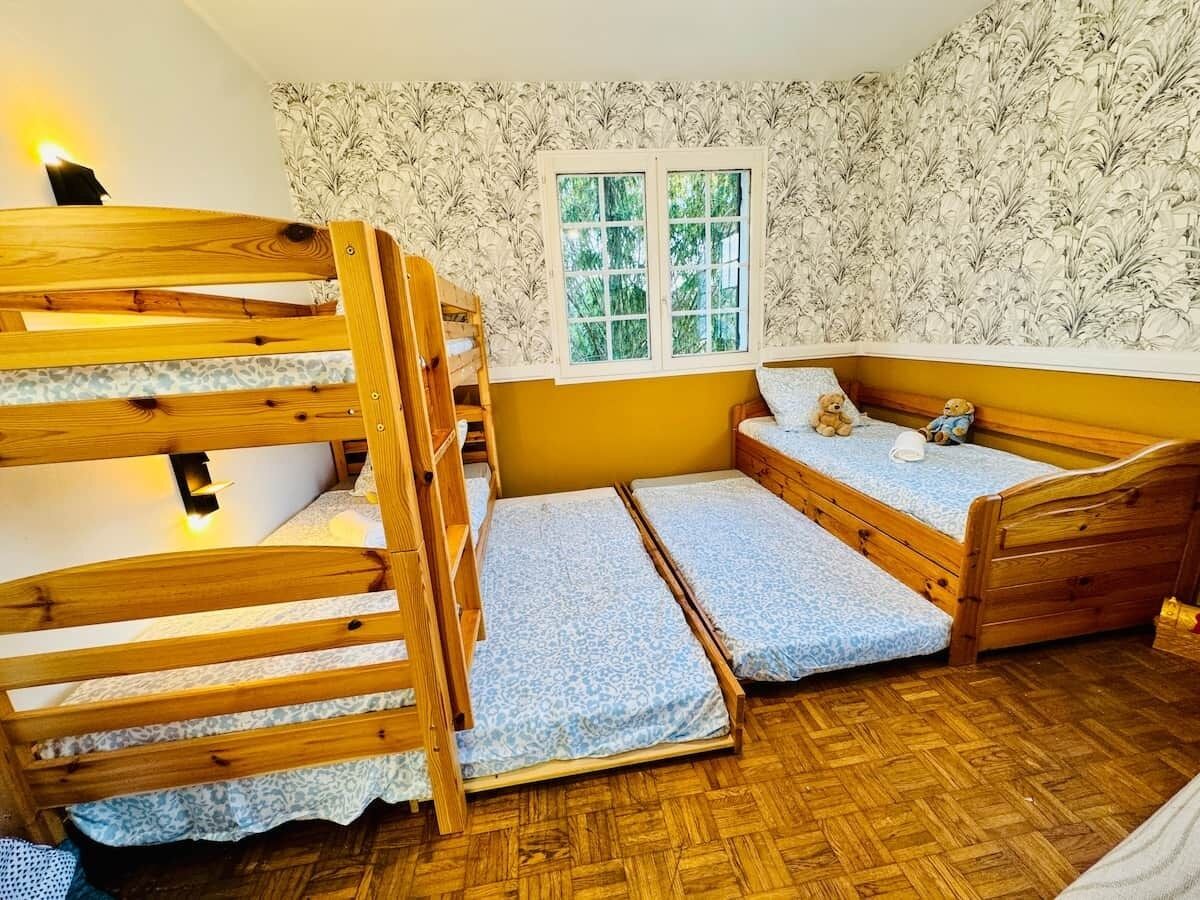Une chambre avec des lits superposés, une fenêtre et un papier peint à motifs.