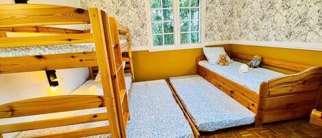 A room with bunk beds, a window, and a patterned wallpaper.