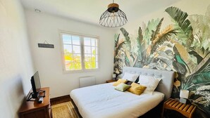 A bedroom with a bed, a nightstand, a desk, a window, and a wall mural. - Logement 100m² - La Villa' Tyno - 9 couchages (La Teste-de-Buch)