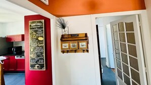 A room with a red wall, a sign indicating an open bar, a menu board, and a door leading to another room. - Logement 100m² - La Villa' Tyno - 9 couchages (La Teste-de-Buch)