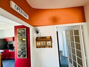 Ein Zimmer mit roter Wand, einem Schild für eine offene Bar, einer Speisekarte und einer Tür zu einem weiteren Raum.