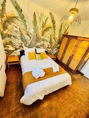 Une chambre d’hôtel comprenant un lit, une table de chevet, une armoire et une fresque murale.