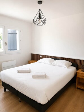 A bedroom with a large bed, two bedside tables, a hanging light fixture, and a window with a view. - Logement RDC - La Villa Tyno Evasion - 60m² (La Teste-de-Buch)