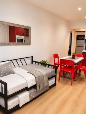 Ein kleines Zimmer mit einem Bett, einem Esstisch und roten Stühlen.