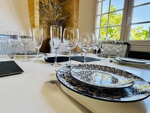 A dining table set with multiple wine glasses and plates, a vase with dried plants, and a window with a view of trees. - Villa' Tyno Excellence familiale - 18 couchages (La Teste-de-Buch)
